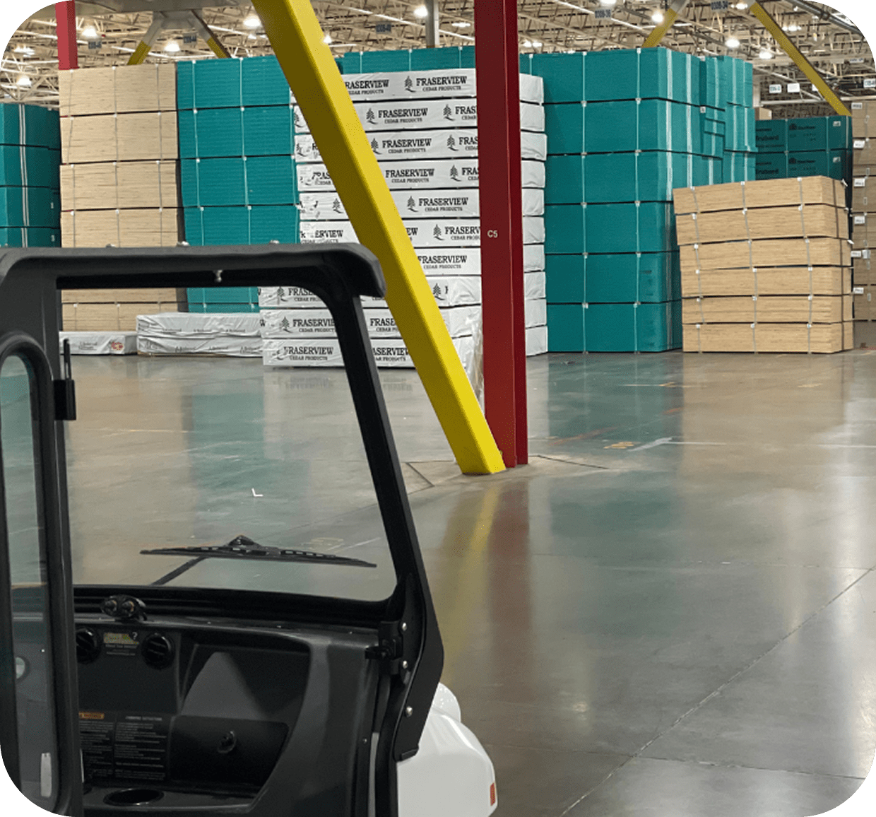 Warehouse with stacked pallets and small vehicle.