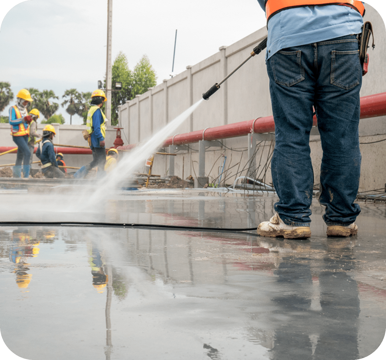 Worker pressure washing construction site floor.