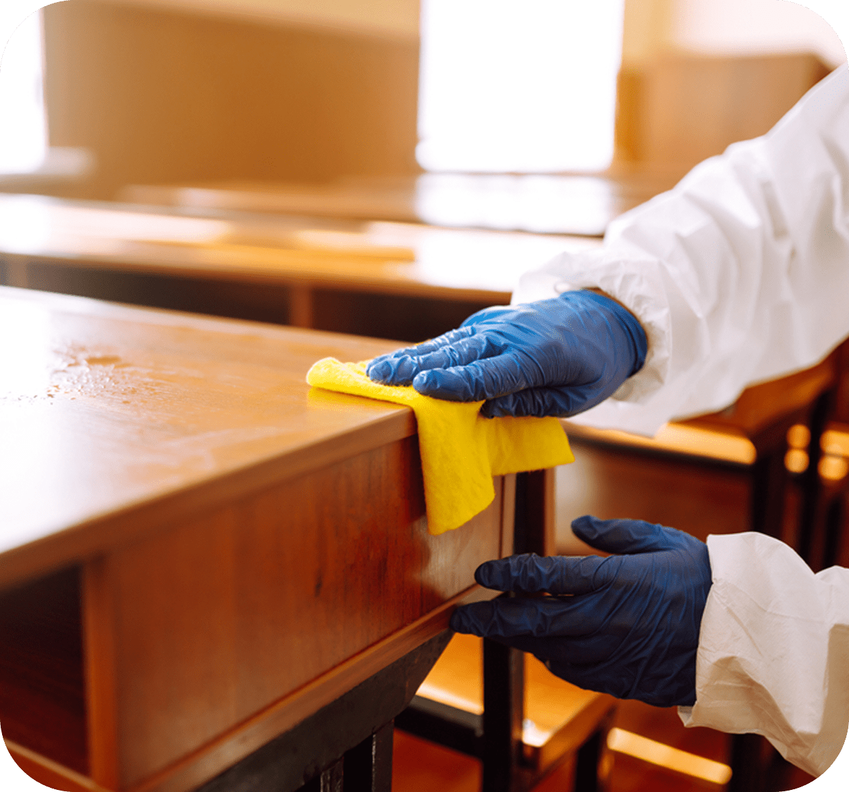 Person cleaning desk with yellow cloth.