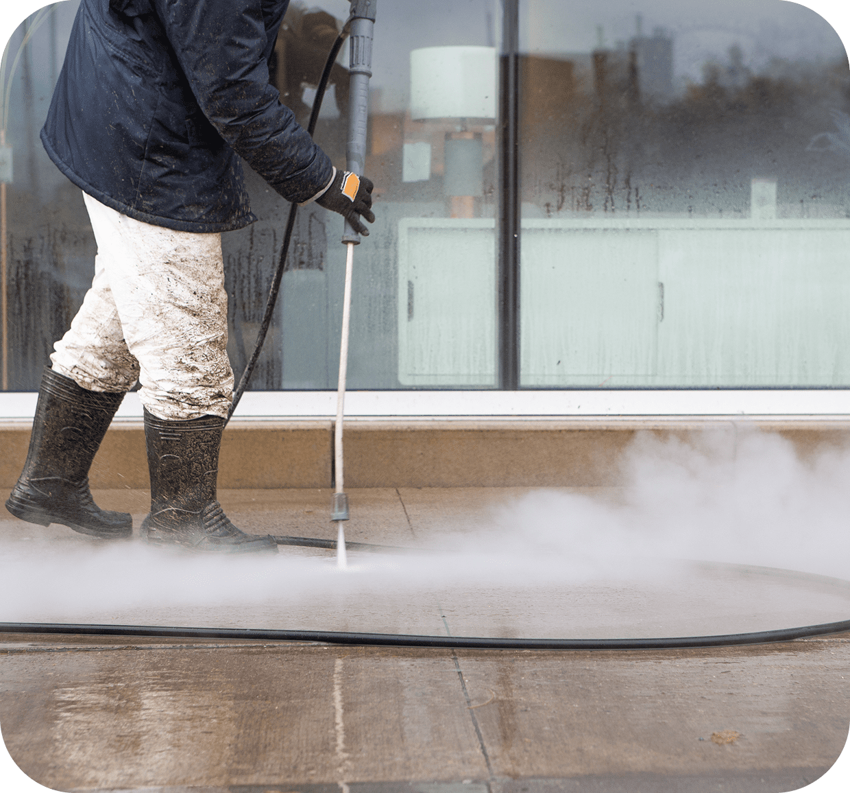 Person pressure washing a concrete surface.